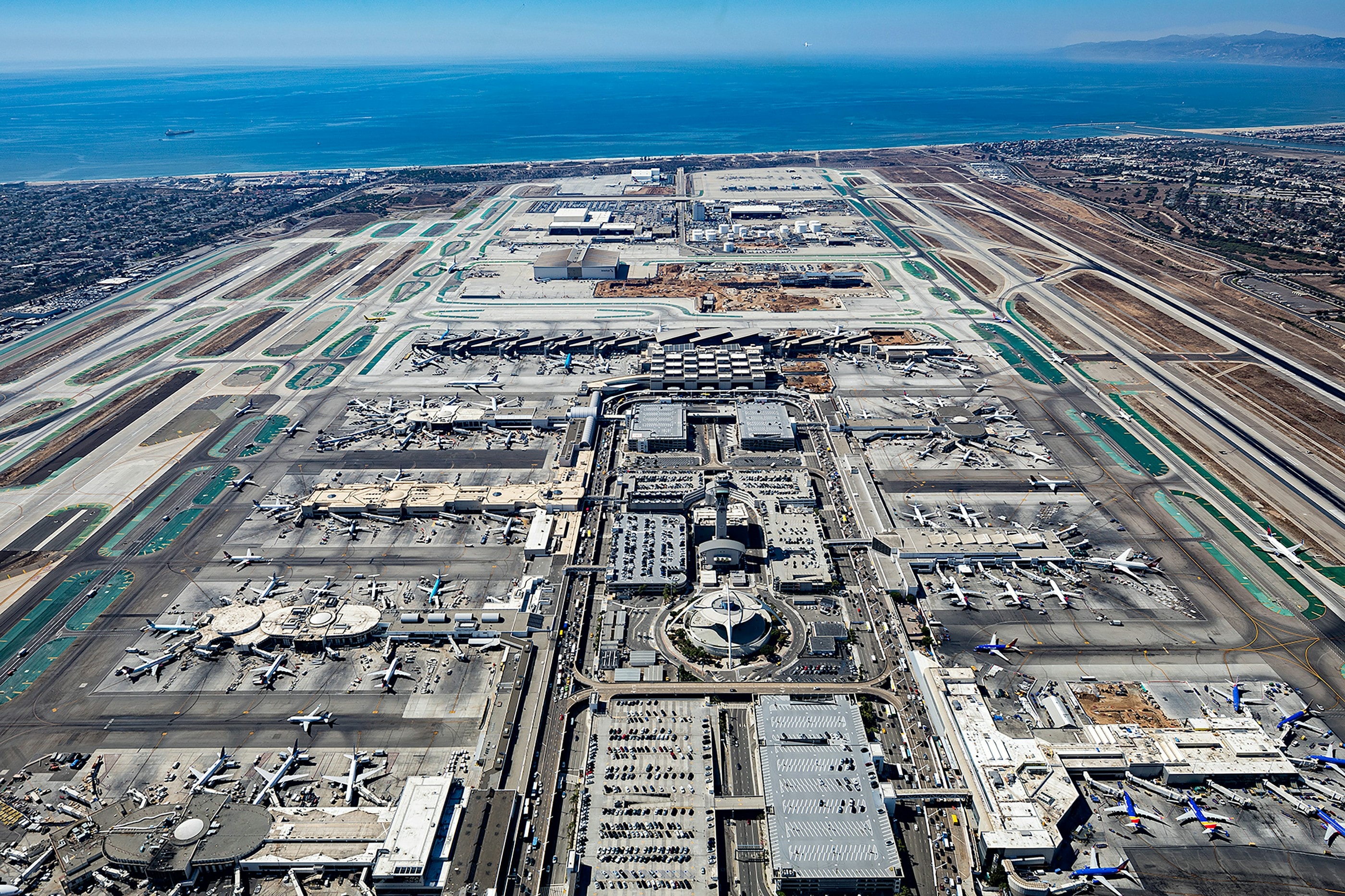 Aerial view of a major airport, with runways on both sides of the terminals