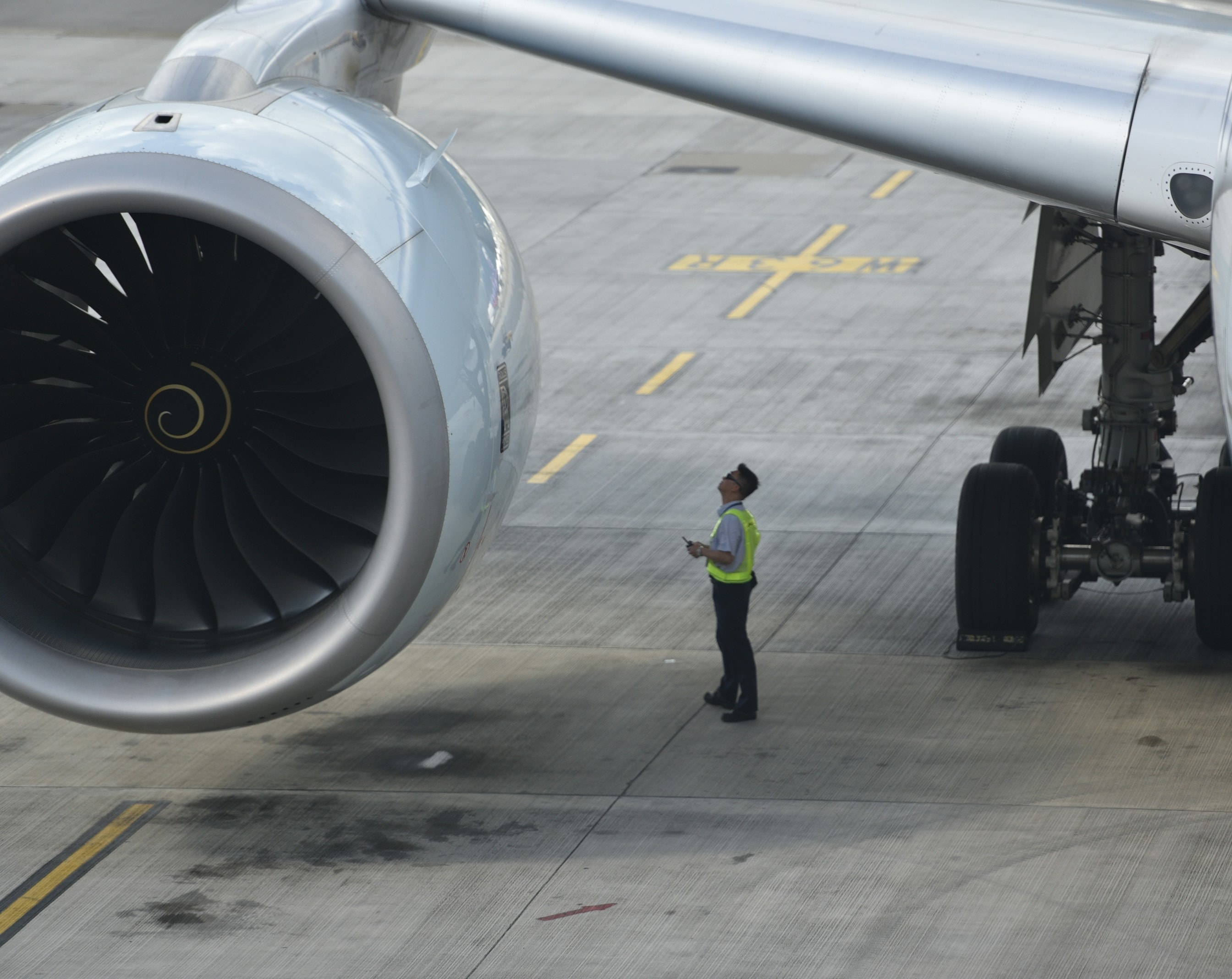 An engineer on the apron inspecting the engine of a wide-body airliner